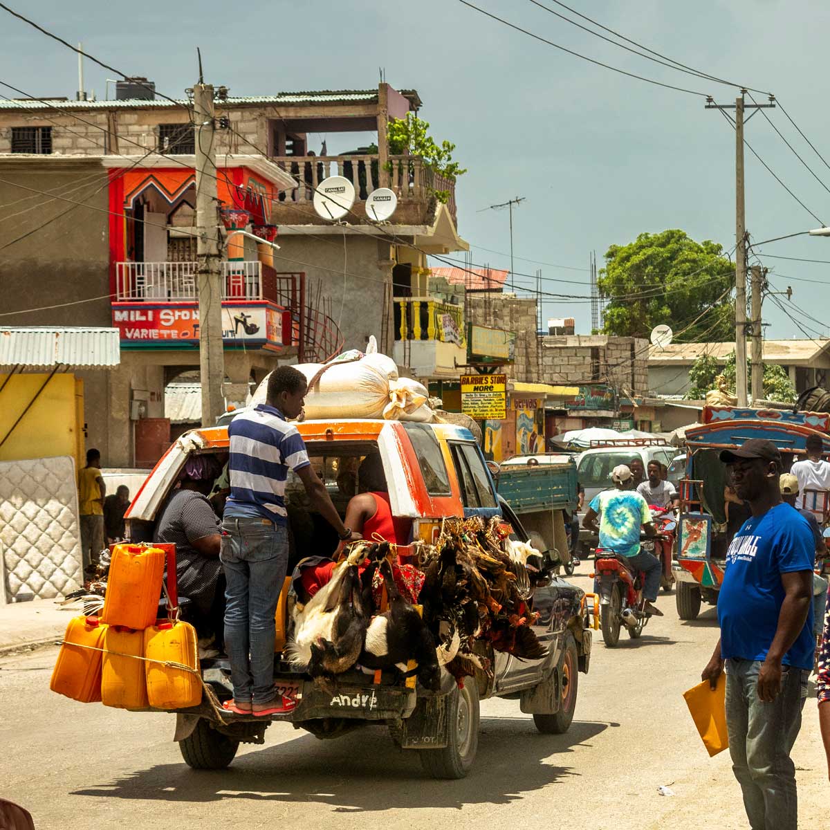 busy city street with bus loaded with goats, chickens and platic containers