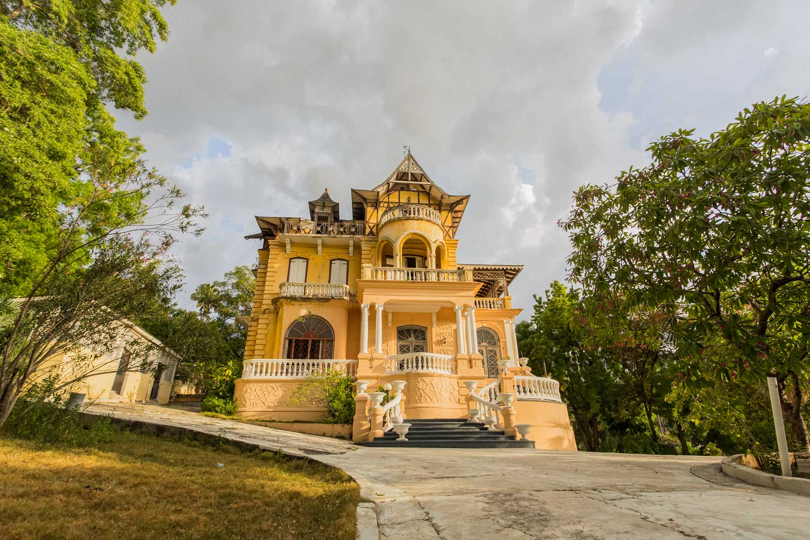 exterior view of old gothic gingerbread mansion with balcony and green trees